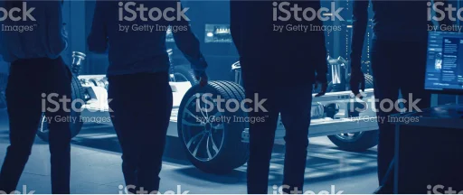 Photo of people looking at the skeleton of a car in the automotive production
